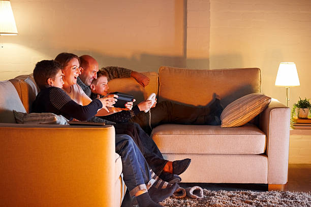 família feliz jogando vídeo game em casa - family sofa night indoors - fotografias e filmes do acervo