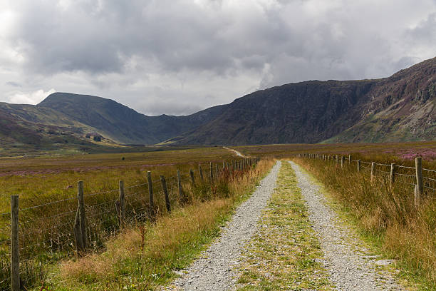 istock Minor road leading into valley surrounded by mountains. 472604504