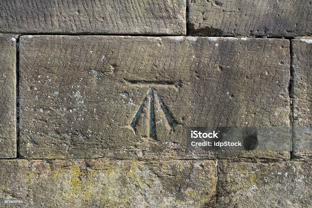 Ordnance Survey (OS) Benchmark An Ordnance Survey (OS) Roadside Benchmark chiseled into a stone wall. Map Stock Photo