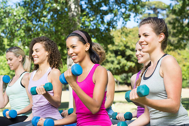 istock Fitness group lifting hand weights in park 472610594