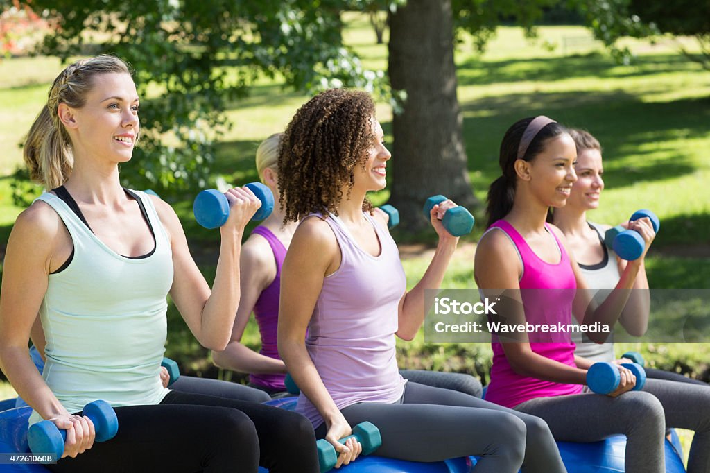 Fitness group lifting hand weights in park Fitness group lifting hand weights in park on a sunny day 20-24 Years Stock Photo