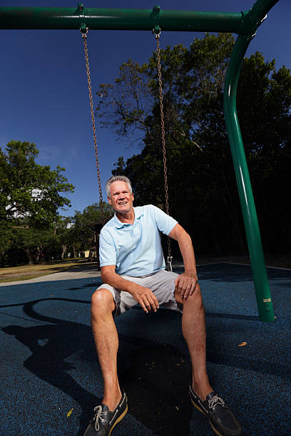 istock Senior man sitting on a park swing 472611282
