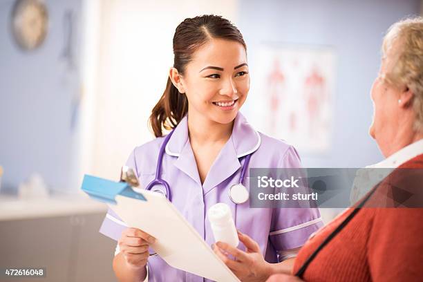 Happy Nurse Chats To Senior Patient Stock Photo - Download Image Now - 20-29 Years, 2015, 70-79 Years