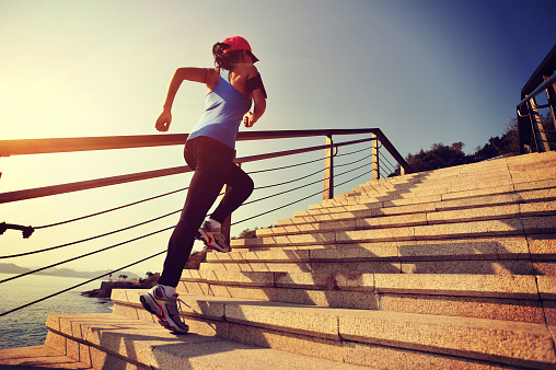 healthy lifestyle sports woman running up on stone stairs  seaside