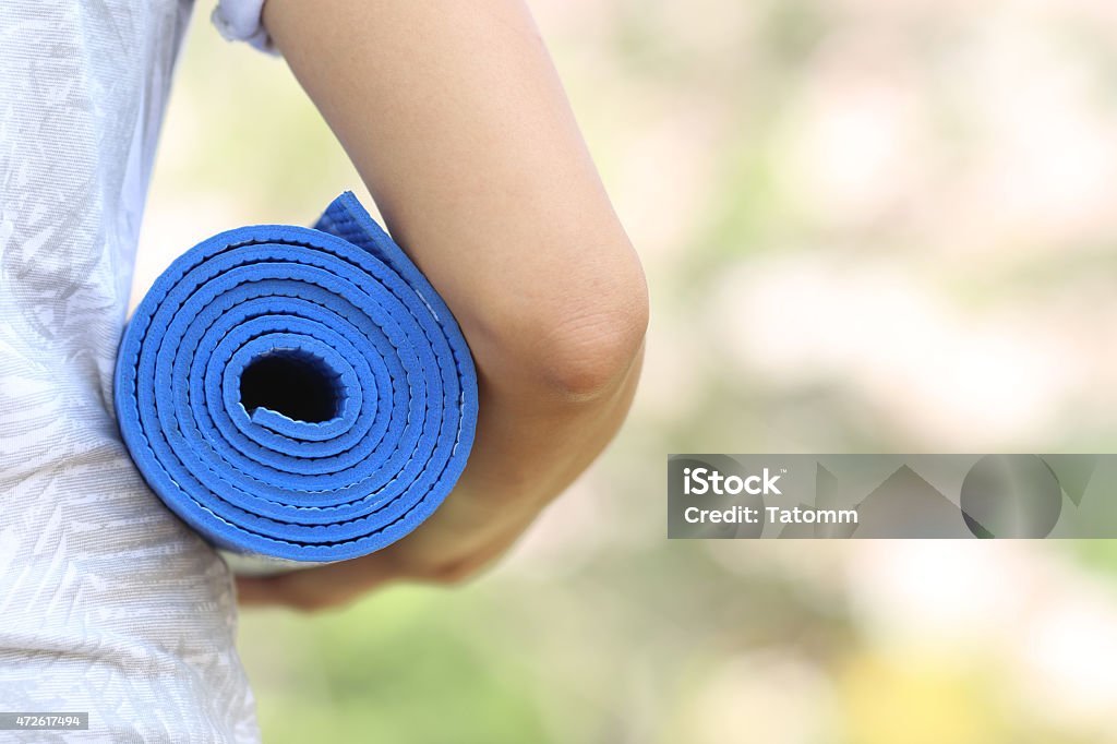 Young woman holding a yoga mat in sakura garden Cherry Blossom Stock Photo