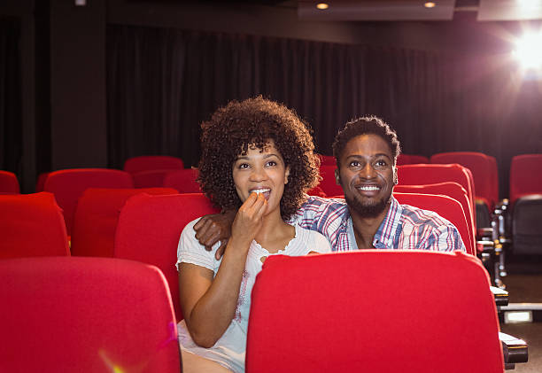 Senior couple watching a dull movie and dozing off in the cinema, sharing popcorn while enjoying a quiet night together