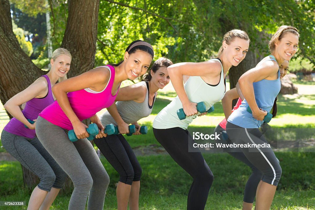 Fitness group lifting hand weights in park Fitness group lifting hand weights in park on a sunny day 20-24 Years Stock Photo