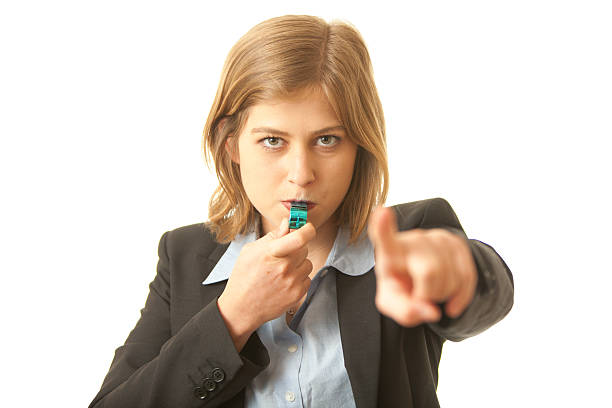 Corporate Whistle Blower Close up of a business woman blowing a whistle and pointing at camera. Concept for corporate whistle blower, or representative of the industry regulator whistleblower human role stock pictures, royalty-free photos & images