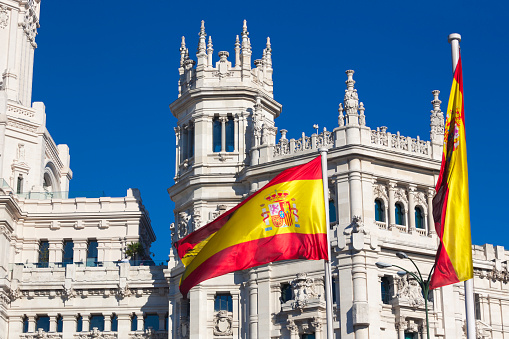 The Cybele Palace (Palacio de Cibeles), the grand city hall of Madrid with a spanish flag blowing in the wind.