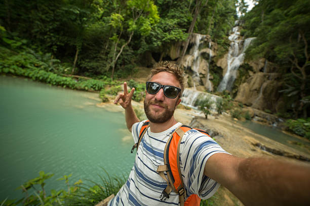 istock Traveler man taking selfie at waterfalls 472629136