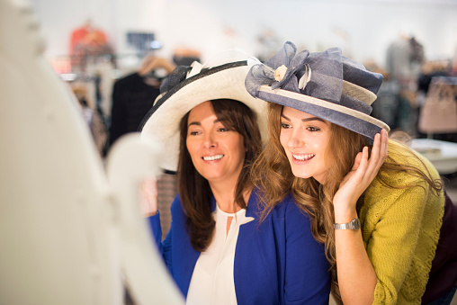 mother and daughter trying hats in a department store.