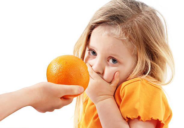 The whimsical child doesn't want to eat orange stock photo