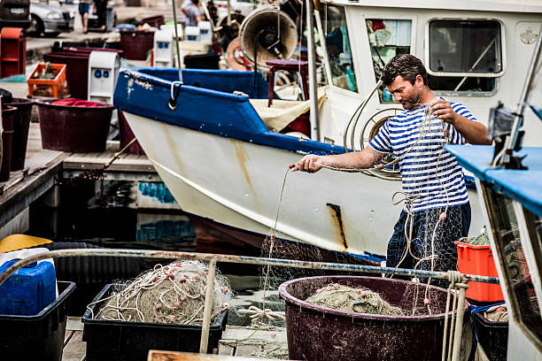 Mature adult fisherman working on the fishing boat moored at the harbor.