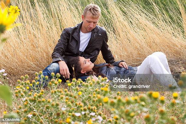 Happy Young Caucasian Couple Relaxing In A Field Stock Photo - Download Image Now - 2015, Adult, Adults Only