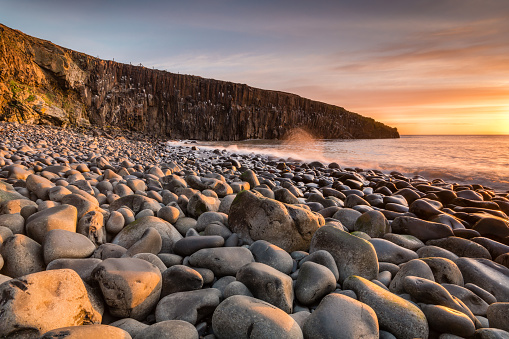 The golden light of early morning lighting the sea washed rocky beach at Cullernose Point in Northumberland