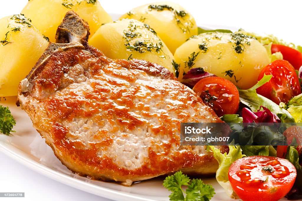 Pork chop, boiled potatoes and vegetables on white background Fried pork chop with vegetables  Boiled Potato Stock Photo