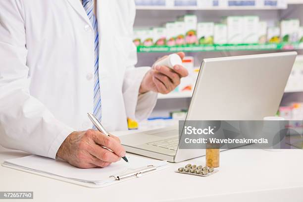 Pharmacist Writing On Clipboard And Holding Medication Stock Photo - Download Image Now