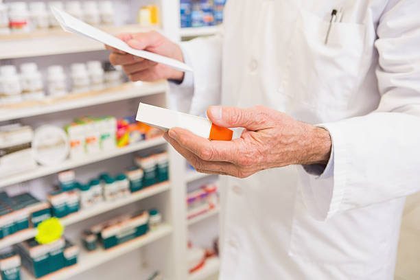 istock Pharmacist looking at prescription and medicine 472658408