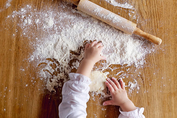 istock Toddler's hands playing with white flour and rolling pin 472660736