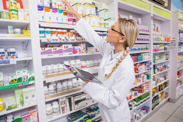istock Junior pharmacist taking medicine from shelf 472660790