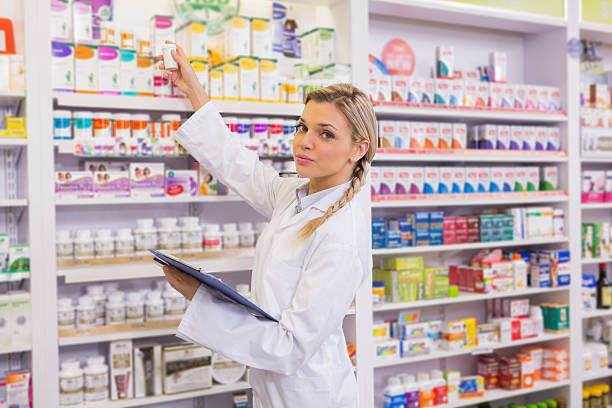 istock Junior pharmacist taking medicine from shelf 472661090