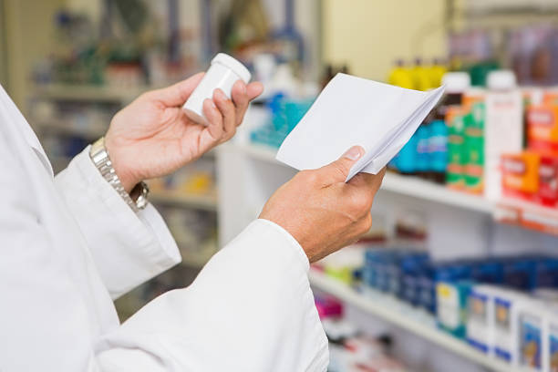 istock Pharmacist reading prescription and holding medicine 472661408
