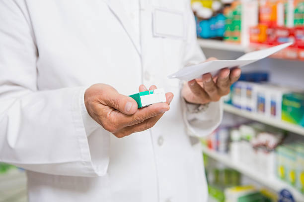 istock Pharmacist reading prescription and holding medicine 472661414