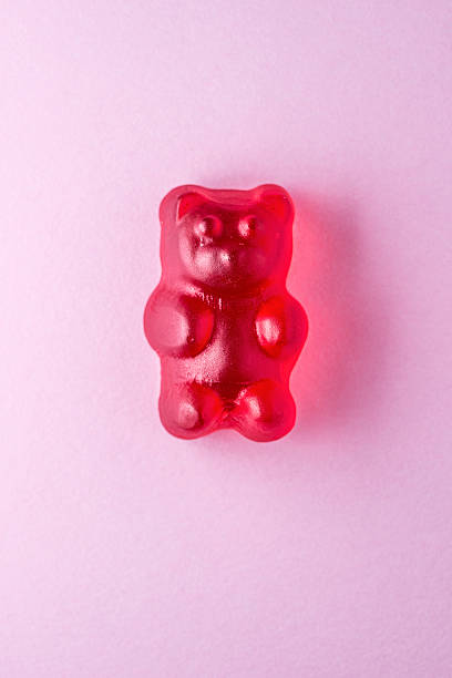 red gummibärchen candy auf rosa papier - gummibärchen stock-fotos und bilder