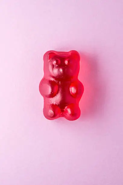 Red gummy bear candy on pink paper