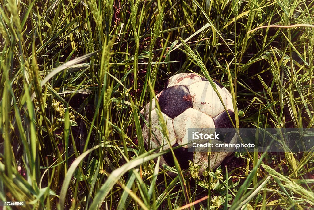 Old worn out vintage soccer ball in tall grass A nostalgic looking photograph of a forgotten old worn out black and white soccer ball in tall grass. This deflated old soccer ball was left outside to rot in tall grass. Deflated Stock Photo