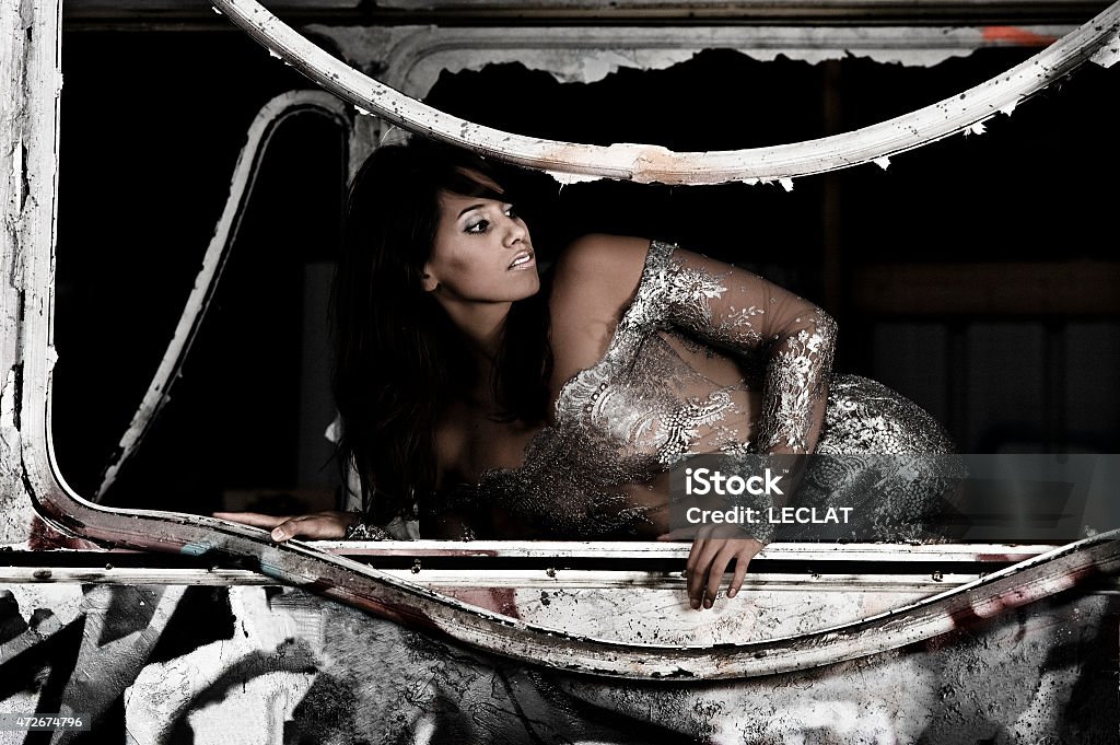 Metal dress turns around A model with a transparent dress turns around and looks behind her. She is in an old rusty bus. 2015 Stock Photo