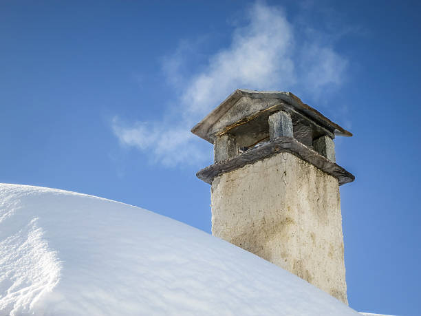 istock Smoke spreading from chimney on snowy roof 472675864