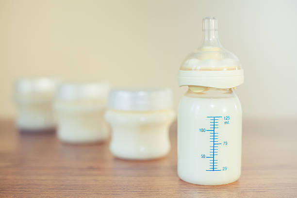 istock Baby bottle with measuring scale filled with milk 472676844