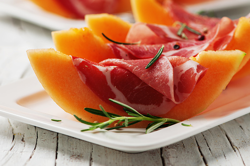 Concept of italian food with melon and prosciutto, selective focus