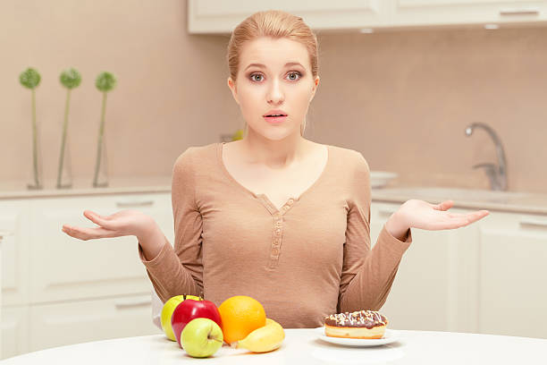 istock Woman making choice between fruit and donut 472678386