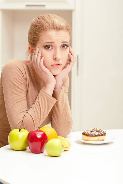 istock Woman making choice between fruit and donut 472678390