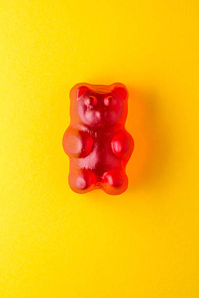 istock Red gummy bear candy on yellow paper 472681826