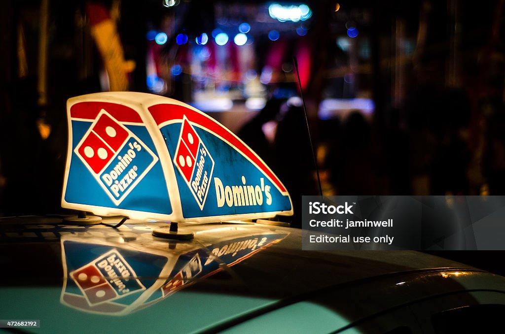 Dominos Pizza car illuminated sign Gros Islet, St. Lucia - May 5, 2015: A Dominos Pizza vehicle is in the night street in Gros Islet district with a sign on its roof advertising the company and showing its trademark logo. Pizza Stock Photo