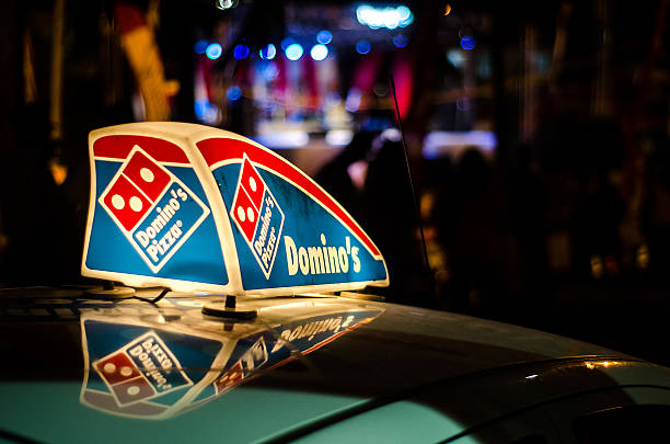 Dominos Pizza car illuminated sign Gros Islet, St. Lucia - May 5, 2015: A Dominos Pizza vehicle is in the night street in Gros Islet district with a sign on its roof advertising the company and showing its trademark logo. domino photos stock pictures, royalty-free photos & images