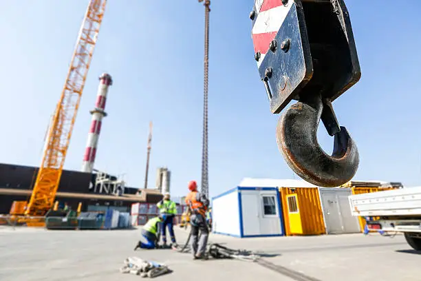 Hook of a mobile lifting crane on a construction site, capable of lifting 25 tons of load with workers in the background. Heavy duty machinery for heavy construction industry.