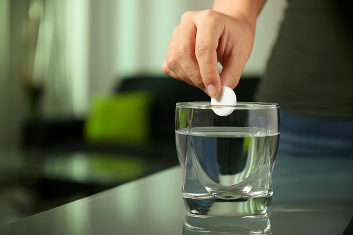 Sick mujer pone comprimido efervescente aspirina en vaso de agua photo