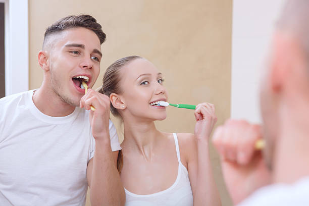 istock Young beautiful couple cleaning teeth 472687276