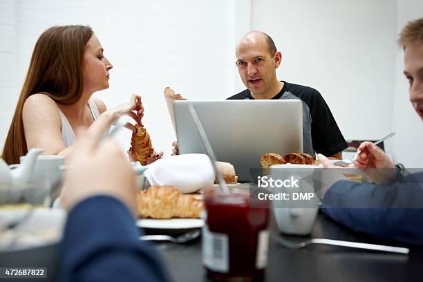 Man Using Laptop While Having Breakfast With Family Stock Photo - Download Image Now