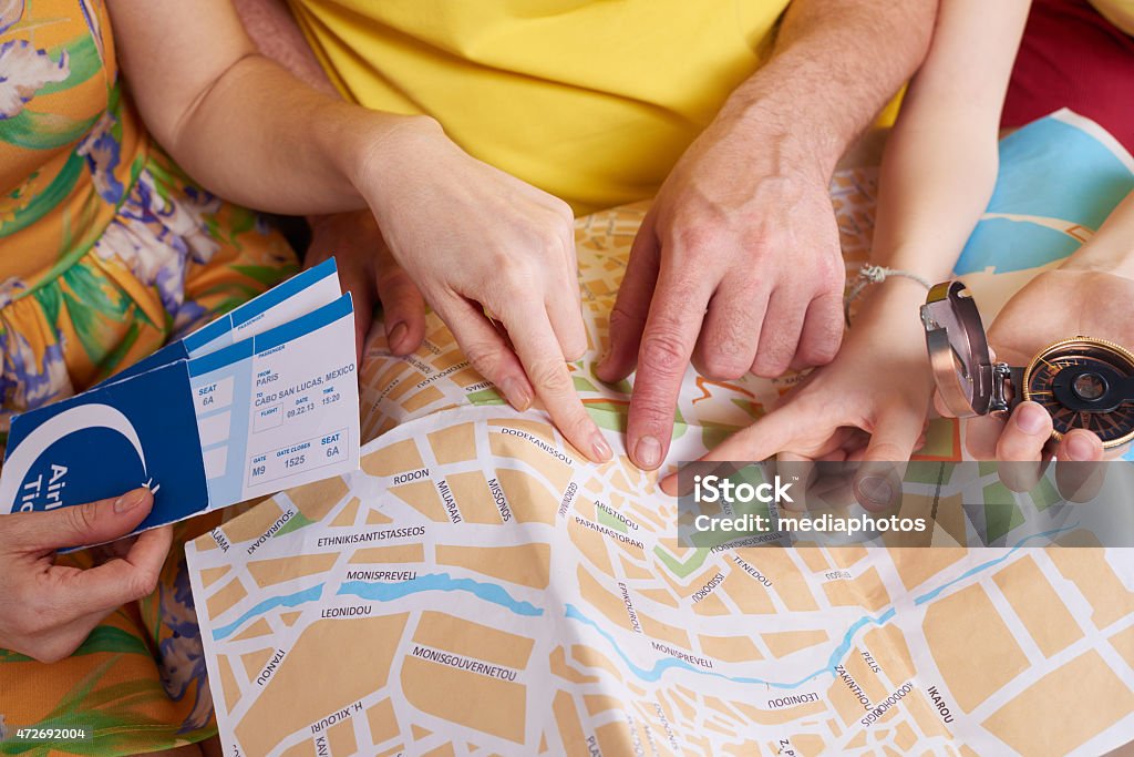 Let's go there Family holding airplane tickets and compass and pointing at spot on map City Map Stock Photo