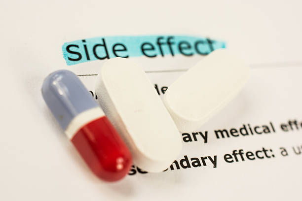 Colored pill and capsules on sheet of medicinal side effects stock photo