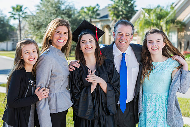 istock High school graduate posing with her family 472693828