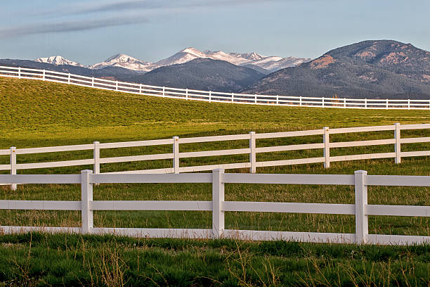 istock Snow Capped Mountain Peaks and white split rail Fencing 472696220