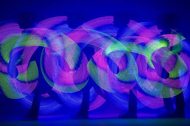 Swirling light of LED poi. Light artist is drawing a circles and curves shapes with a flowtoys. Shooting on long exposure at a studio