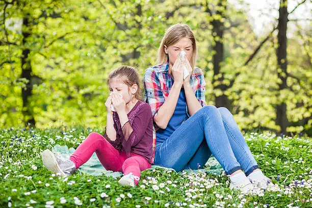 Two women with allergy symptom blowing their noses