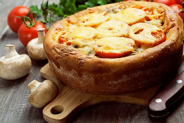 Pie with mushrooms and tomatoes on a wooden table